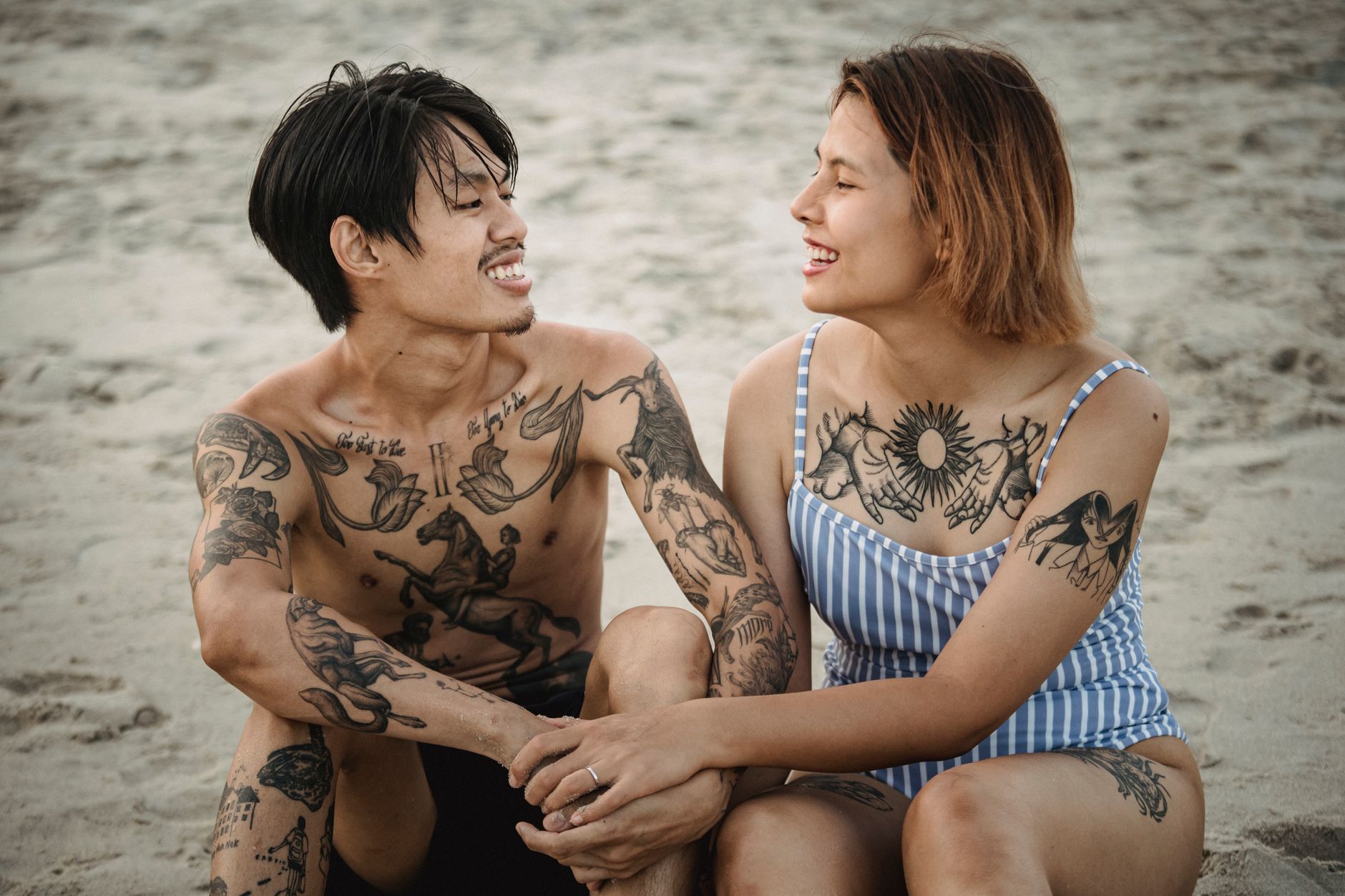 Fashionable woman enjoying beach day with visible Japanese temporary tattoos on arms and legs