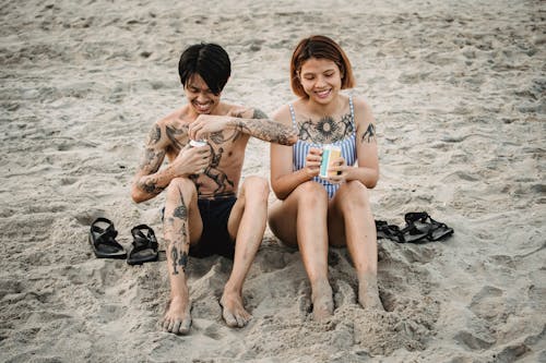 Free Couple Sitting on the Beach and Opening Cans Stock Photo