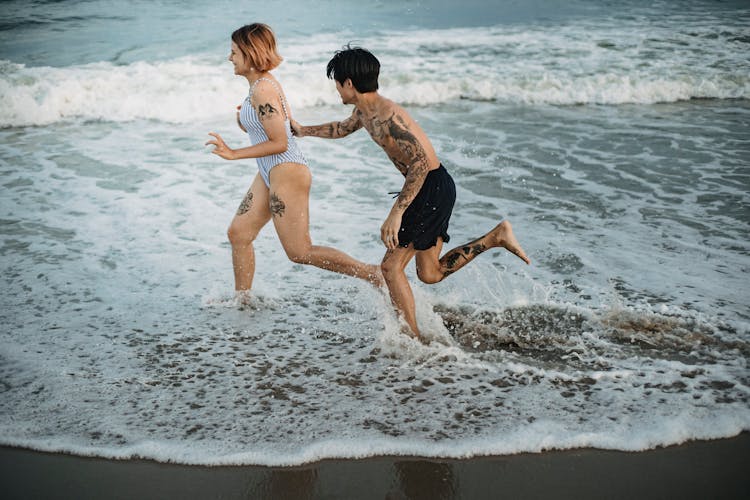 Man Chasing Woman While Playing In Water