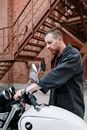 Man in Black Jacket Holding Black and Gray Motorcycle