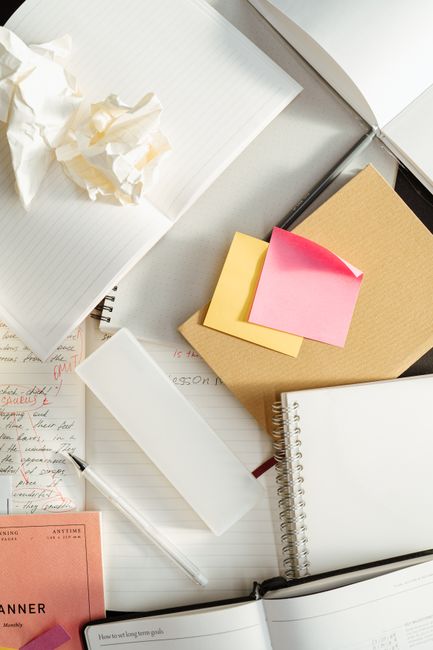 A top-view of assorted stationery and notes, including spiral notebooks and sticky notes.