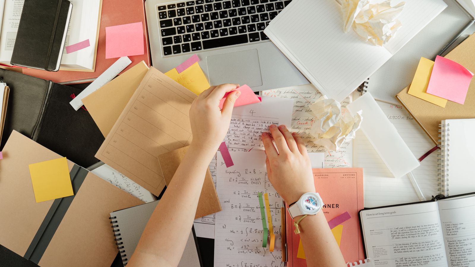 A person holding printed papers in a home-office workspace