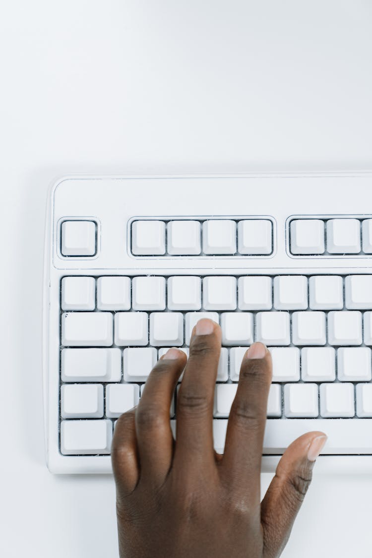 Close Up Shot Of Hand Typing On White Keyboard 