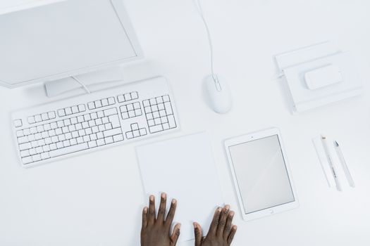 顶视图：一个极简风格的白色办公室工作空间，摆放着小工具，并有人手入镜