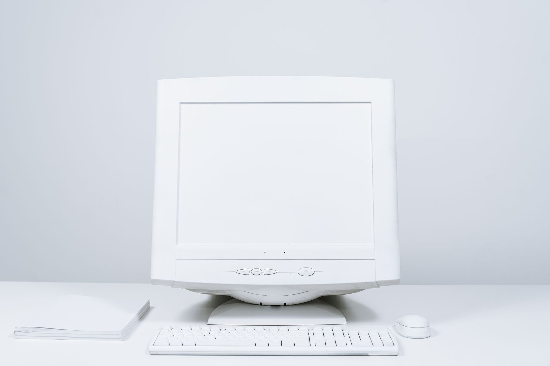 A minimalist white computer setup including monitor, keyboard, and mouse on desktop.