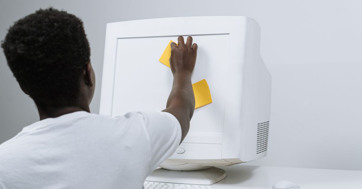 A person writing in a journal with a sticky note that says