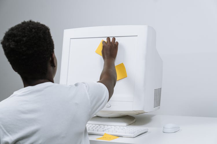 Back View Of A Man Putting Sticky Notes On A Monitor