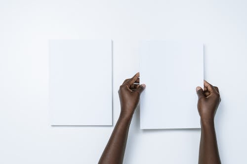 Person Putting White Papers on a White Wall