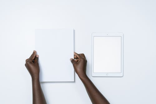 Placing a White Paper Beside a White Tablet with Blank Screen