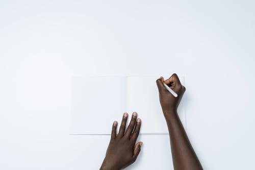 Free Person Writing on a White Notebook Stock Photo