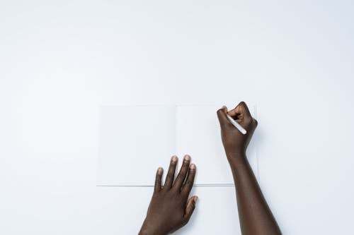 Person Writing on a White Notebook