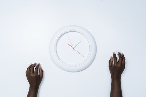 Person Holding a Computer Mouse Beside a Clock