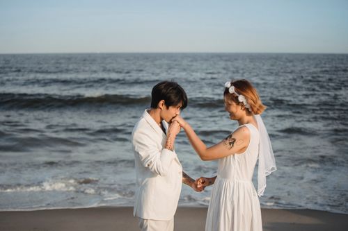 Free A couple sharing a romantic moment on a beach during their wedding ceremony. Stock Photo