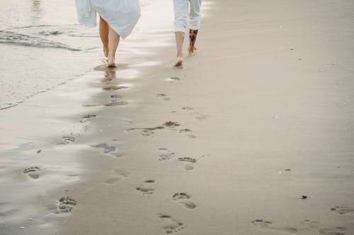 Footsteps of Couple Walking on Beach Together