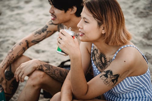 Tattooed Couple Sitting on a Beach 