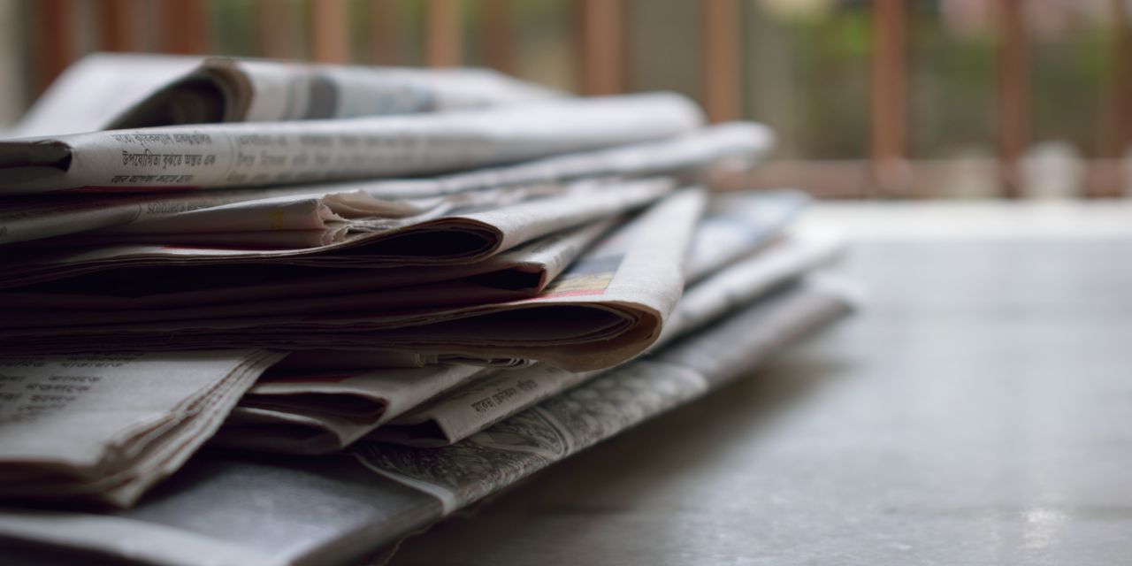 A close-up stack of newspapers on a desk, each one competing on its headline, the craft behind SEO headlines that get clicks