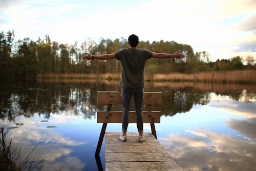 Free Man Standing on Boardwalk on Front of Body of Water Stock Photo