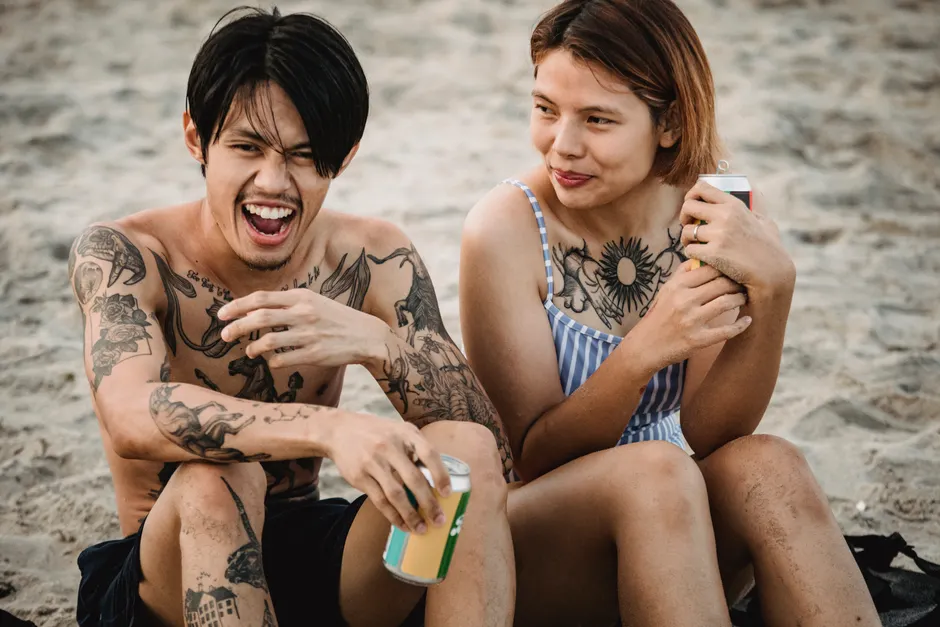 Couple profitant de la plage avec des tatouages temporaires visibles, style décontracté et fun