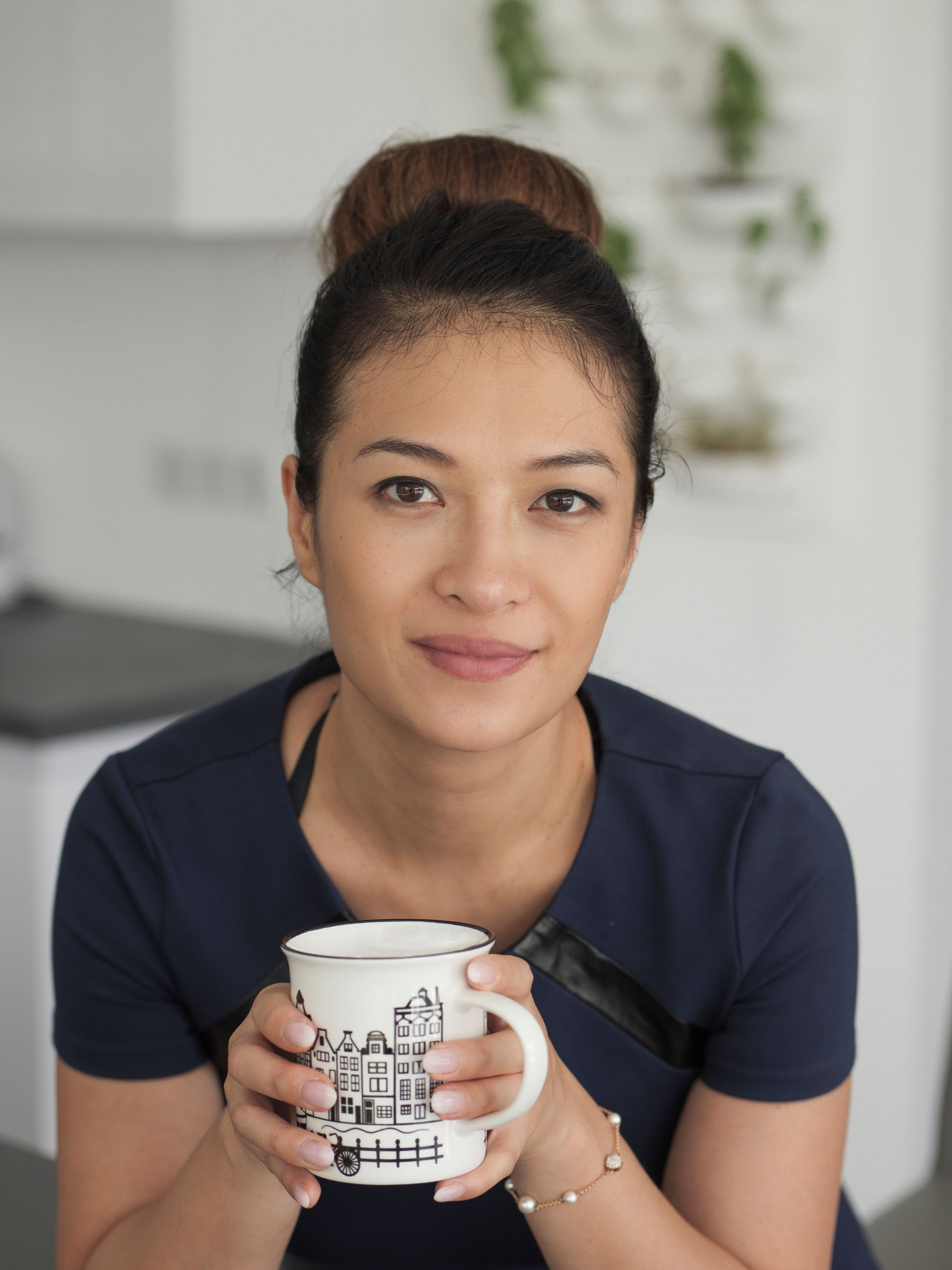 Portrait of a woman holding a stylish mug, captured indoors with a soft and warm atmosphere.