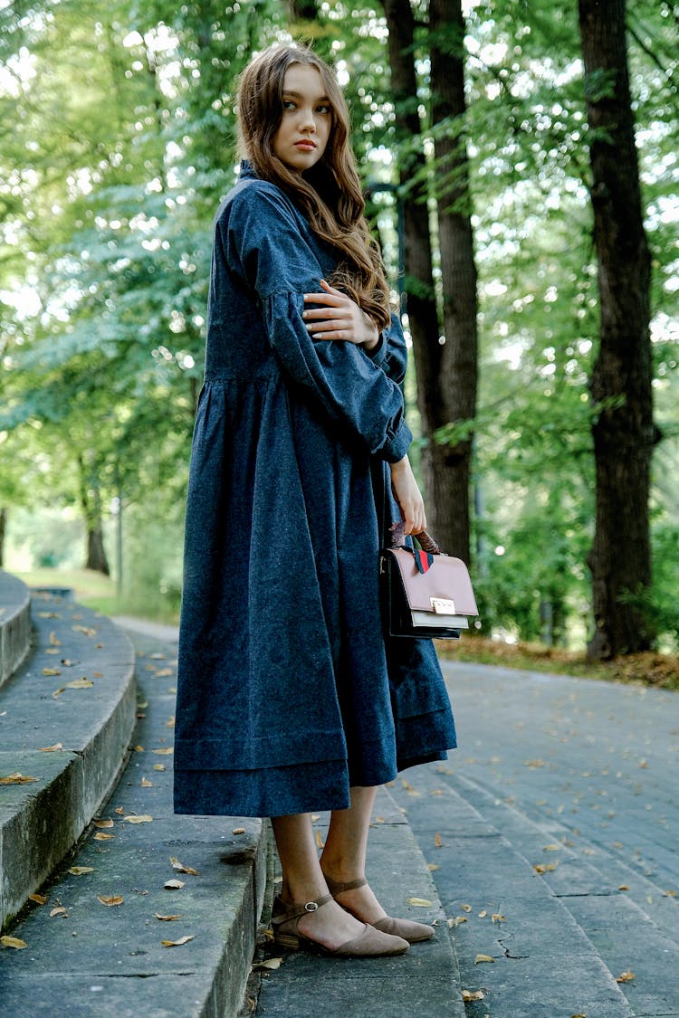 Serene Woman In Loose Dress Standing On Park Staircase