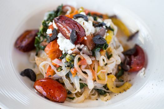 Savor this vibrant Mediterranean pasta salad with fresh veggies and feta cheese.