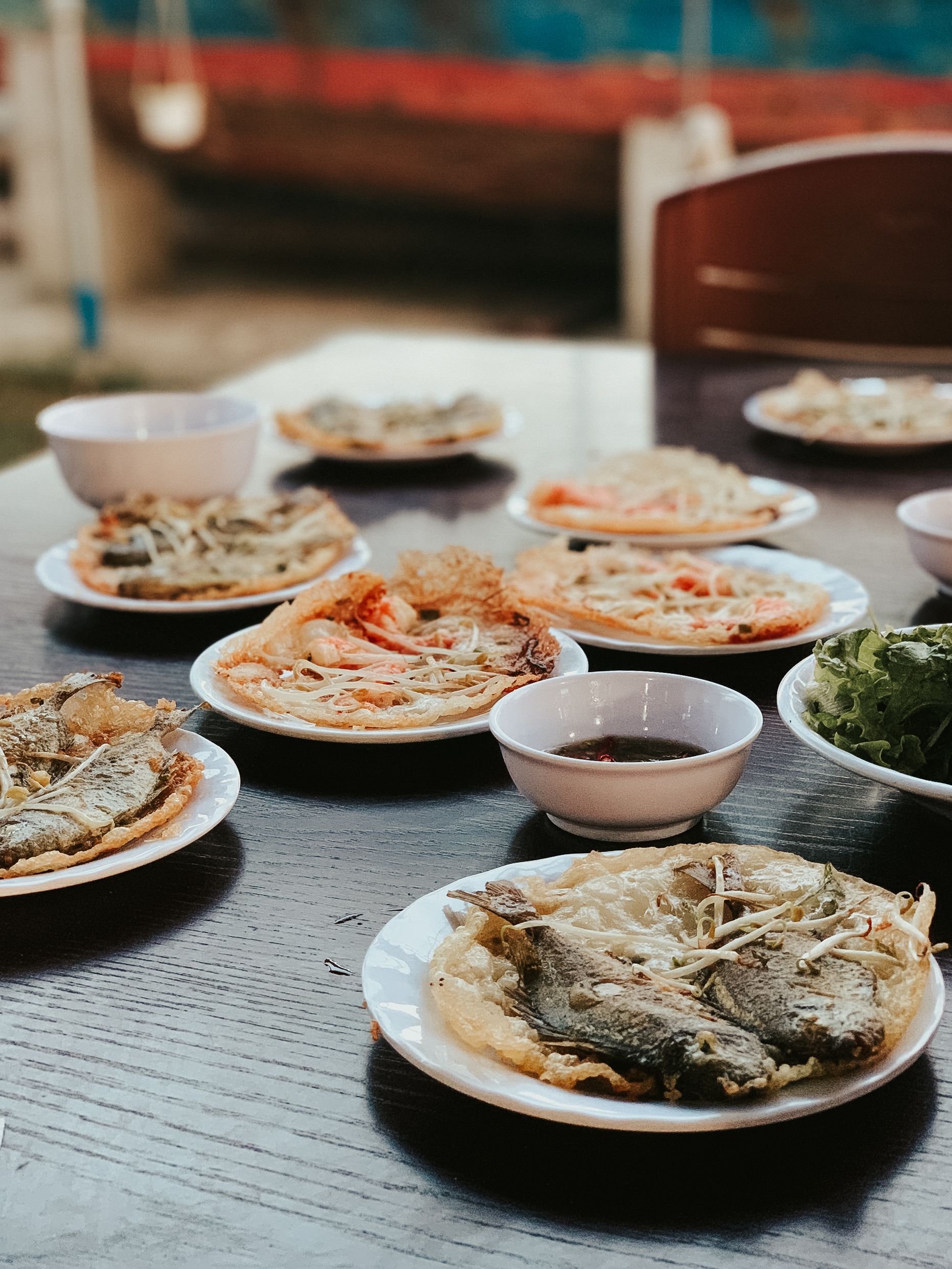 A variety of traditional Vietnamese pancakes served on a wooden table outdoors.