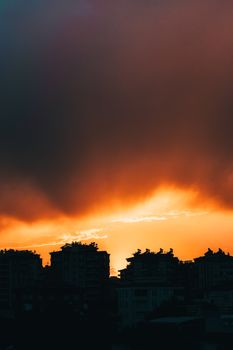 A beautiful silhouette of city skyline during a vibrant sunset with dramatic clouds.
