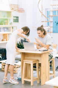 Young professionals collaborating in a modern office with a laptop on a wooden desk.