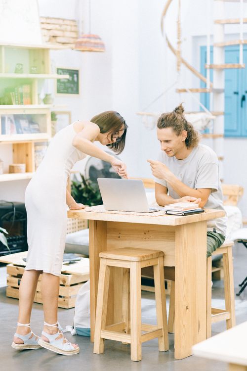 Free Young professionals collaborating in a modern office with a laptop on a wooden desk. Stock Photo