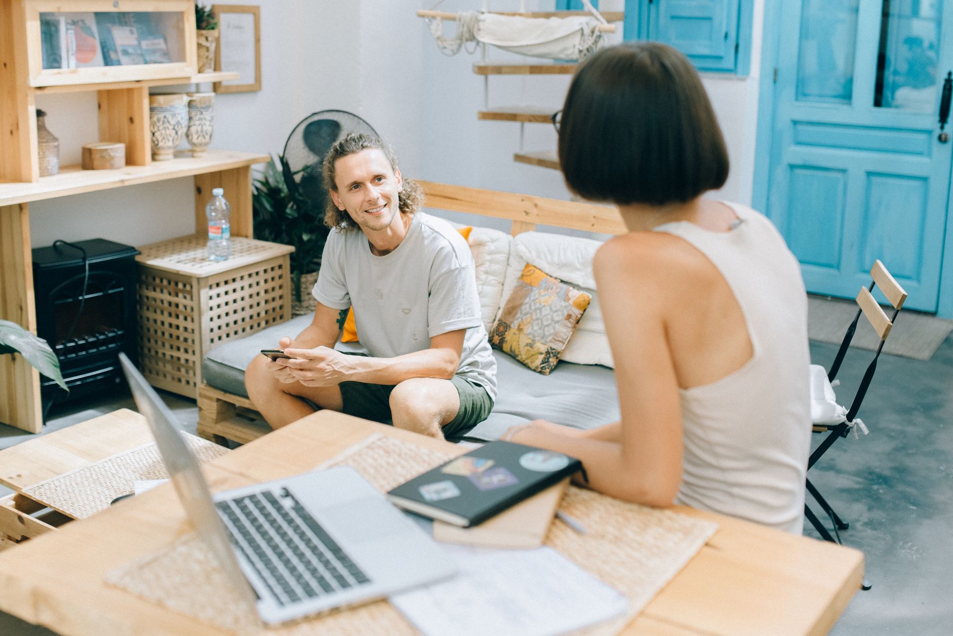 A relaxed meeting between colleagues in a modern workspace with natural decor and open laptops.