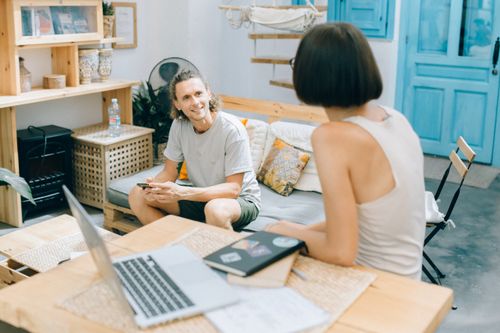 Free A relaxed meeting between colleagues in a modern workspace with natural decor and open laptops. Stock Photo