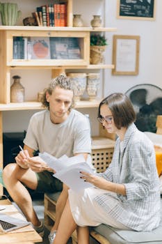 A man and woman discussing documents in a cozy workspace setting.