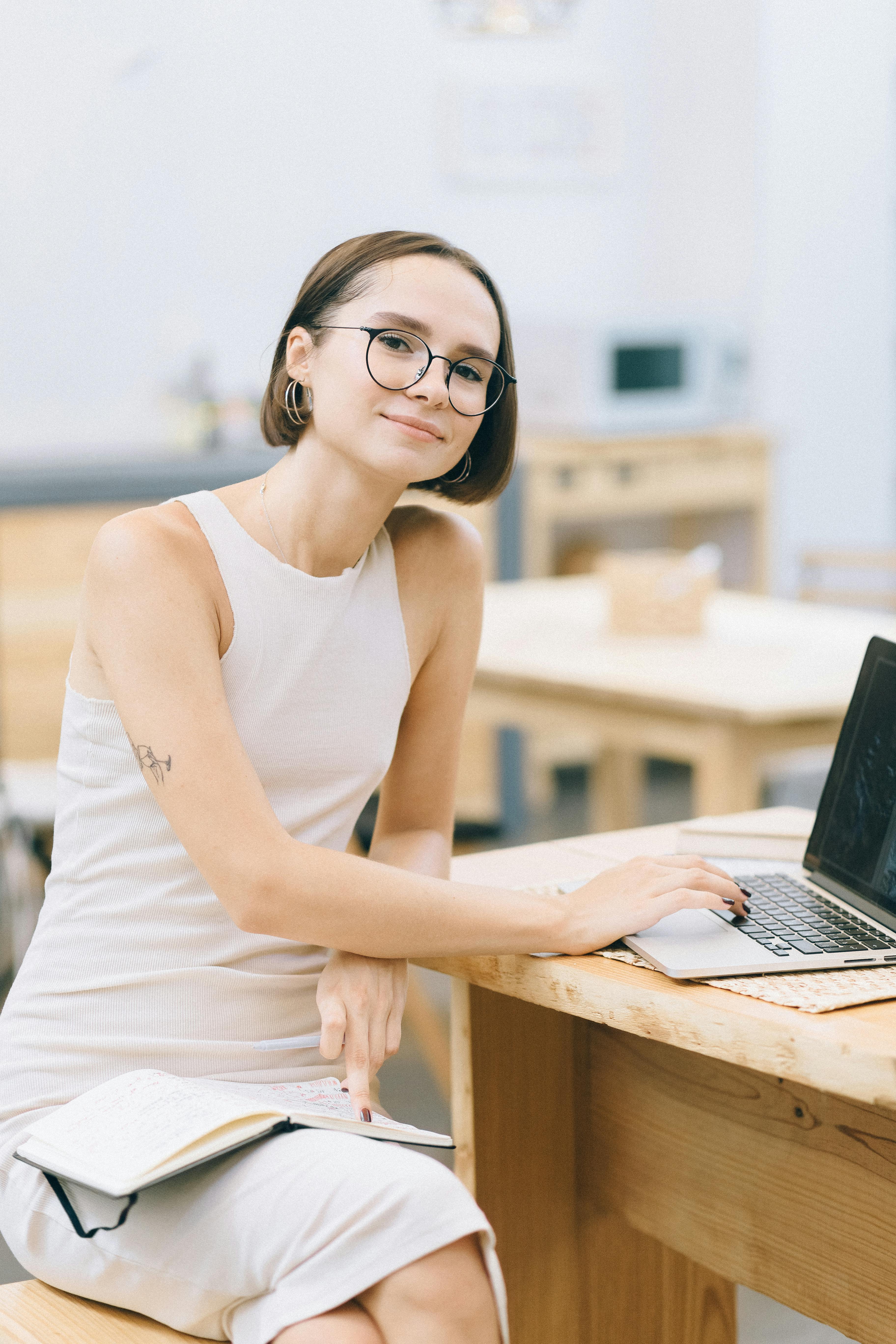 在舒适的咖啡馆里，一位自信的年轻女性正用笔记本电脑工作，这体现了远程工作文化