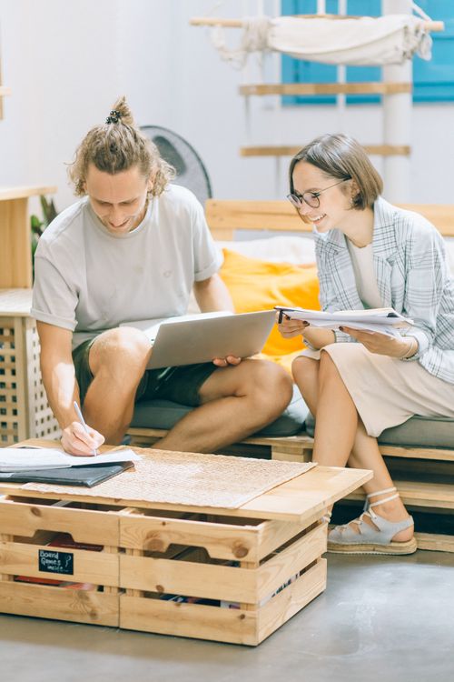 Free Two colleagues smiling and collaborating over work in a casual office setting. Stock Photo