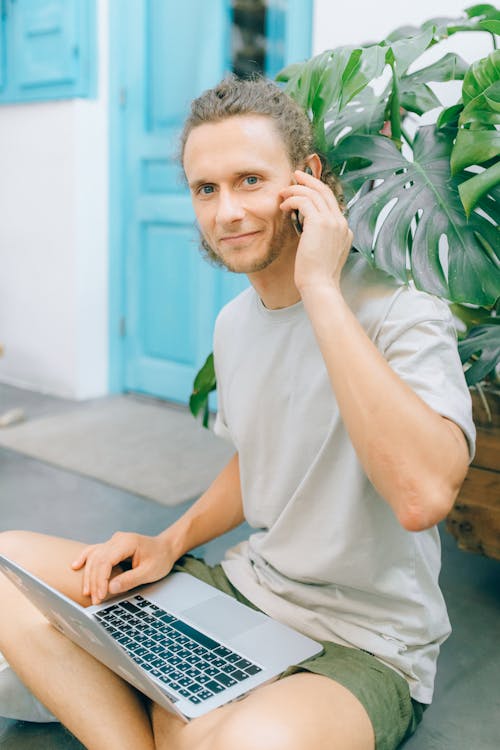 A Man Using a Laptop while on a Phone Call