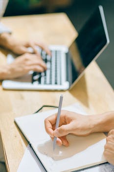 两个人用笔记本电脑在办公桌上合作，强调团队合作