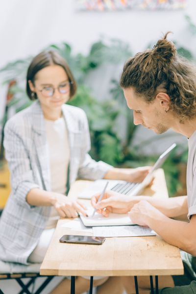 Two colleagues reviewing notes at a shared desk — photo by Nataliya Vaitkevich on Pexels