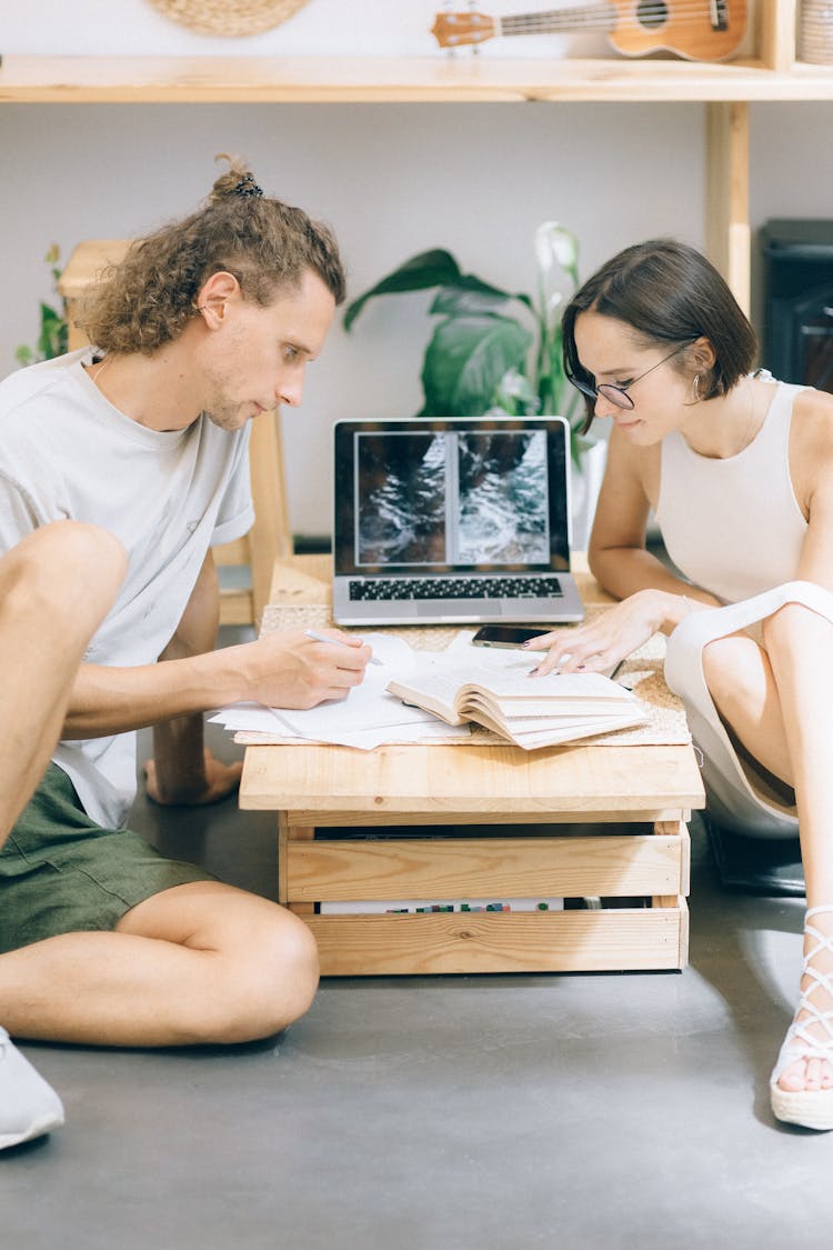 Man And A Woman Working Together While Sitting On The Floor