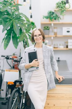 一位穿着时尚的女性站在现代化室内办公空间里，周围种植着植物