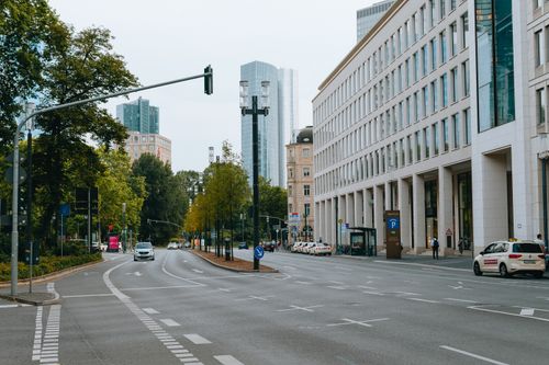 Free A city street view with skyscrapers, cars, and lush trees on a clear day. Stock Photo