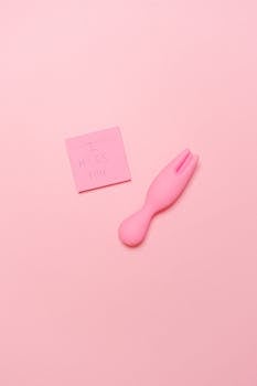 Minimalist photo of a pink vibrator and 'I miss you' note on a pastel pink background.