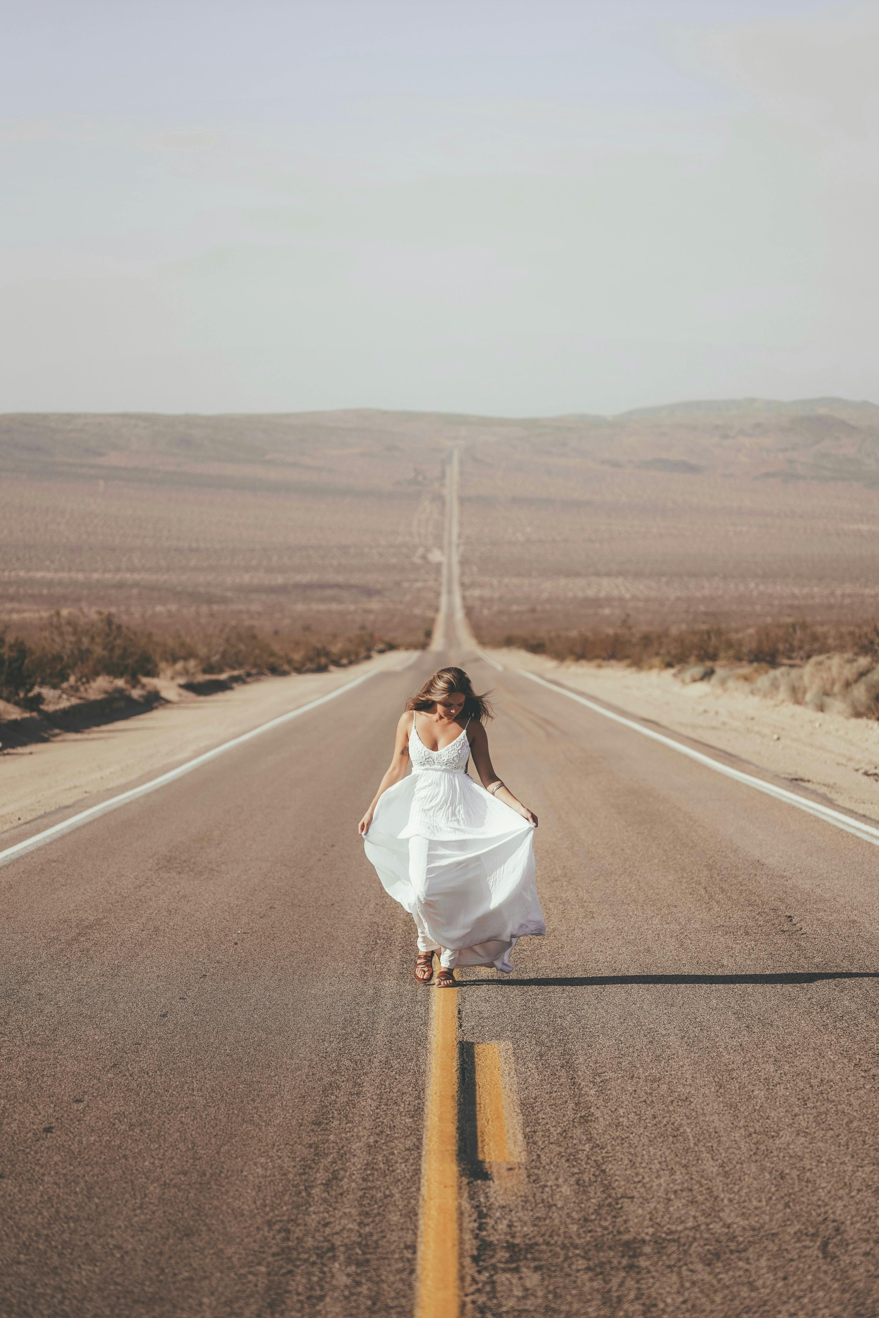 unrecognizable woman walking along road in countryside