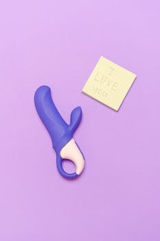 A purple silicone vibrator next to a sticky note saying 'I love you' on a lavender surface.
