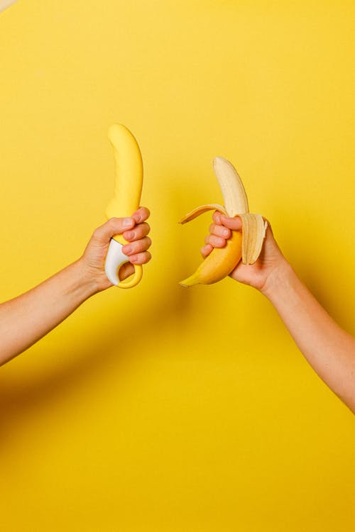 Free Hands Holding a Banana and a Sex Toy Stock Photo