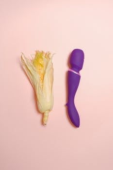 A creative still life concept featuring an ear of corn and a purple vibrator on a pastel background.