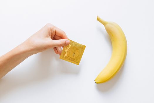 Person Holding Condom Next to Banana