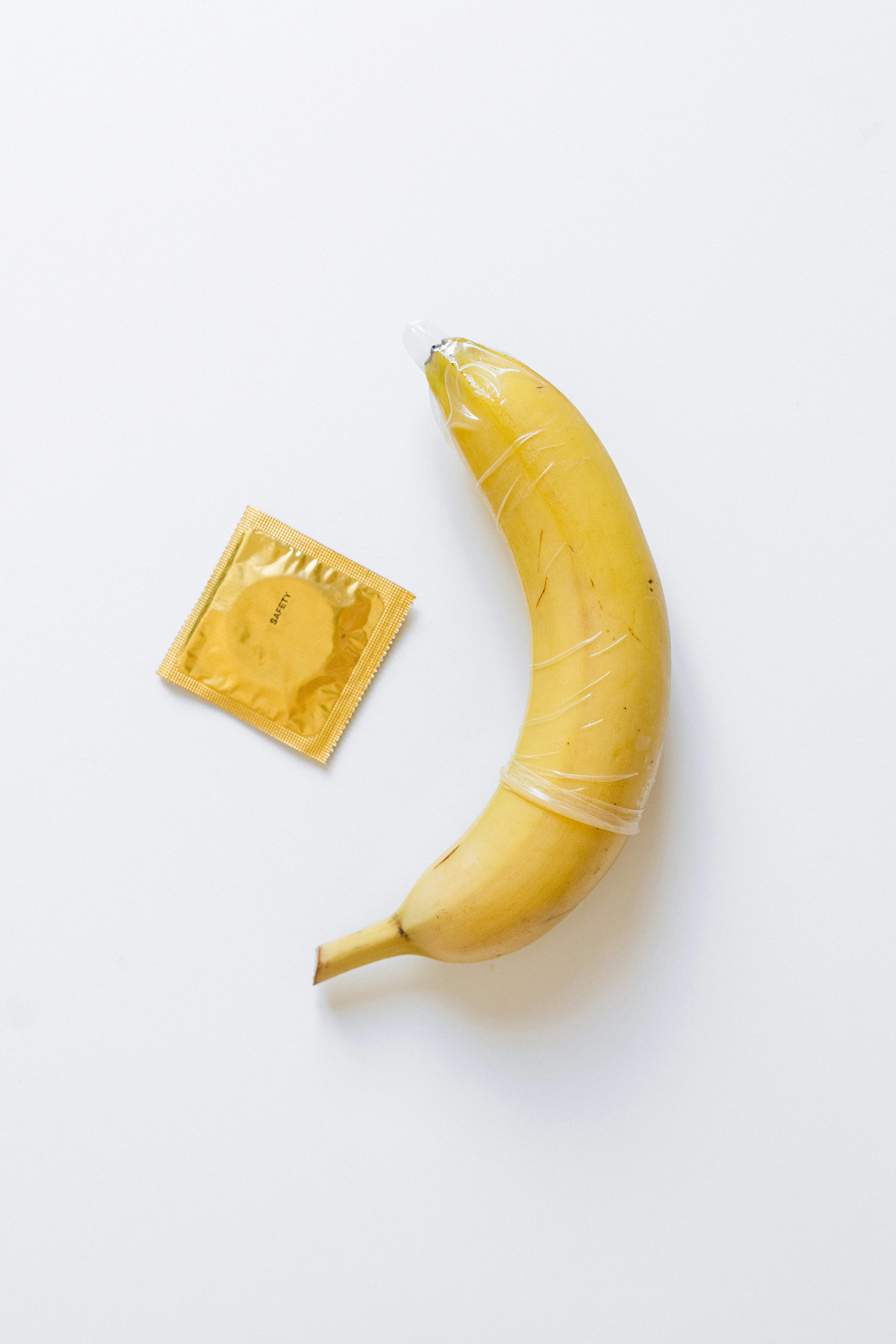 Person Wrapping Condom on Banana · Free Stock Photo