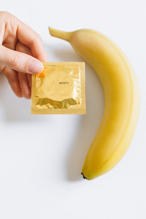 Person Holding Condom Next to Banana