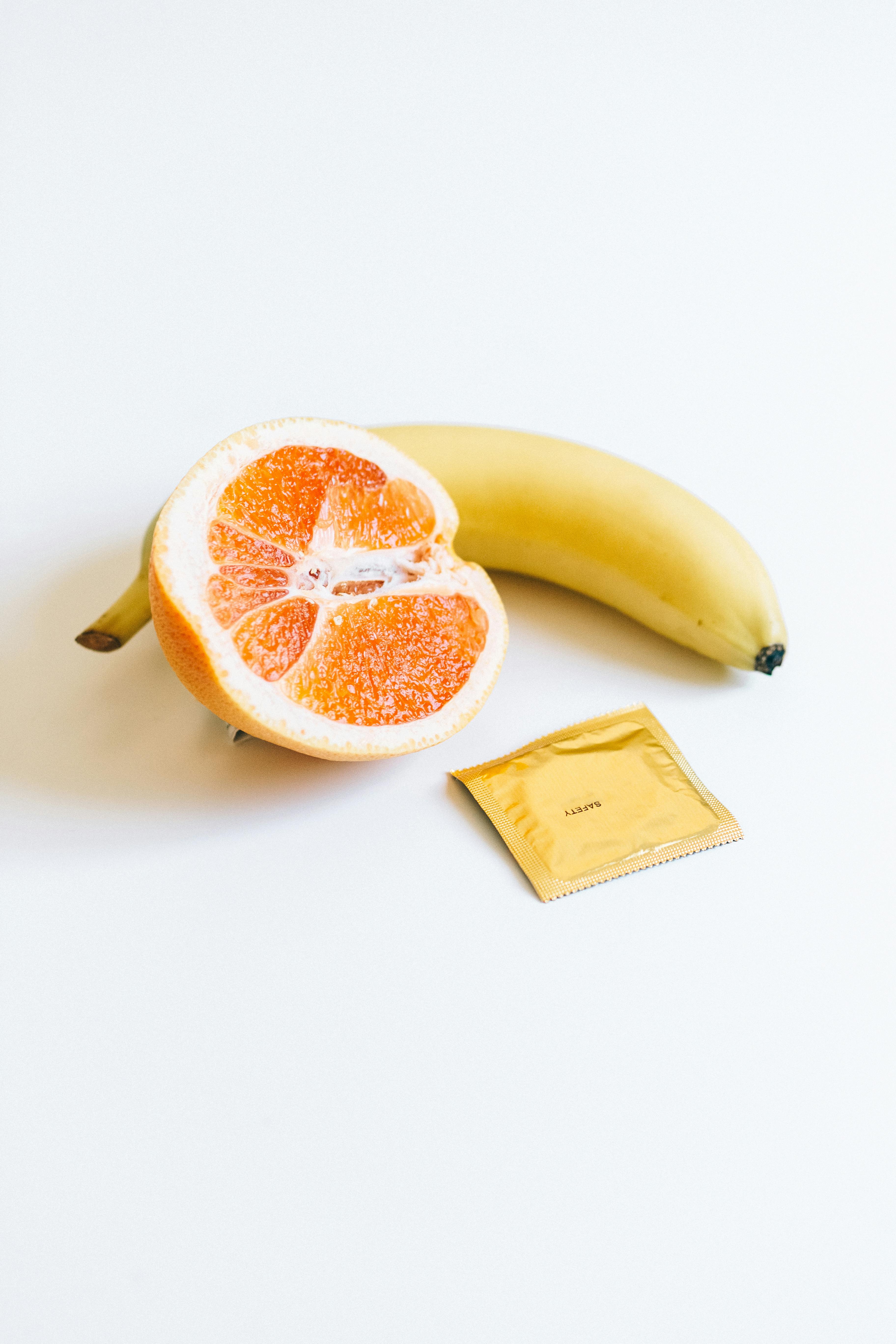 condom next to banana and orange fruit