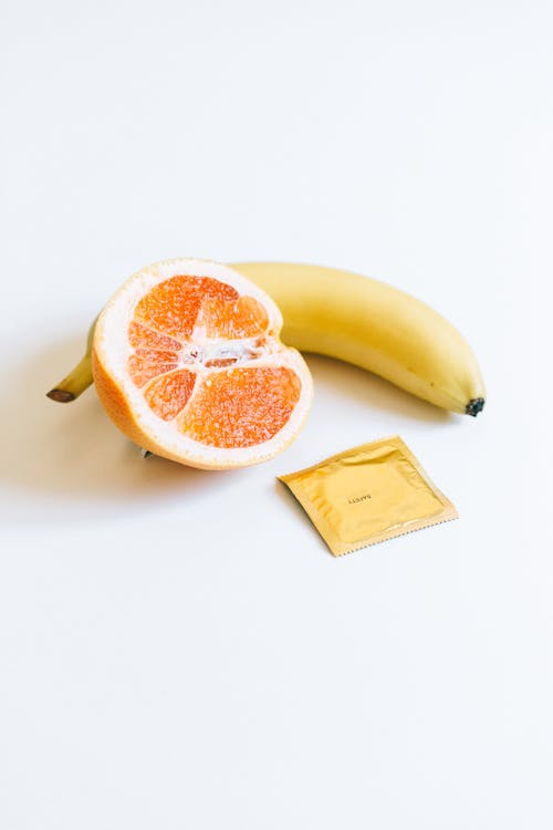 香蕉和橙色水果旁邊的避孕套